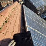 a man fitting pigeon guarding to solar panels on a roof top in barnsley