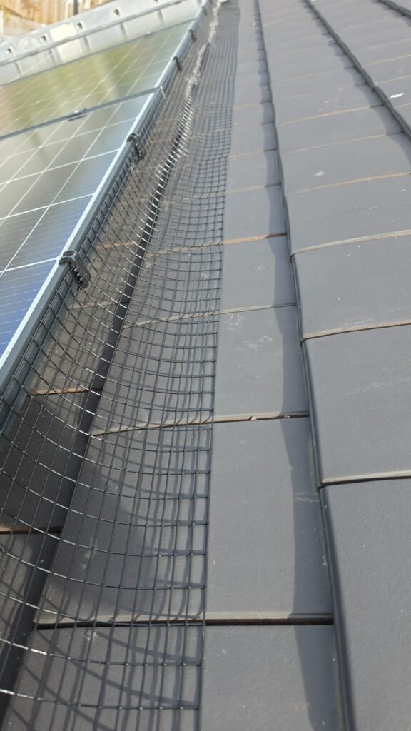 35mm UV-rated Solar Fast Fix clips securing black PVC-coated pigeon-proofing mesh to solar panels in Chapeltown Sheffield.