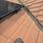 UV-rated Solar Fast Fix clips securing black PVC-coated pigeon-proofing mesh to solar panel frames.
